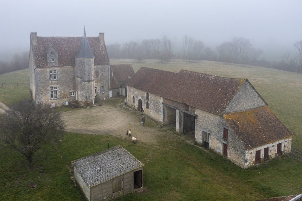 Le manoir des Rosiers à Reveillon. C’est l’un des derniers manoirs, peut-être même le dernier, à se présen- ter ainsi à nous. Le manoir des Rosiers n’a guère évolué depuis le début du XVIe siècle, époque de sa construction. C’est aujourd’hui une ferme des plus traditionnelles. La petite route qui y mène cède la place, quelques dizaines de mètres avant l’entrée, à un chemin de terre. Si l’on excepte les abris cou- verts de tôles et les marches neuves pour accéder à la porte de la tour, rien ou presque ne semble avoir changé.Le potager, à l’avant du manoir, les pâtures et les champs de part et d’autre, témoignent d’un usage agricole immémorial. Pas de jardin d’agrément, de bordures de buis, encore moins de piscine. Les Rosiers, un manoir paysan qu’une nouvelle « noblesse » urbaine n’a pas encore converti en résidence de loisirs. Photographie extraite du projet photographique "les manoirs du Perche"