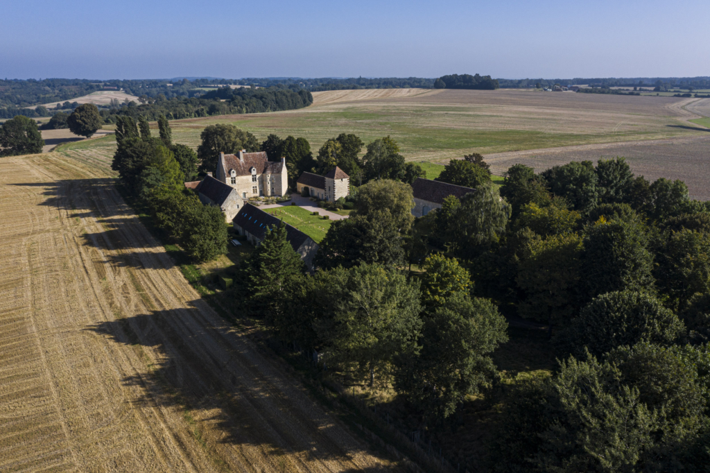 Le manoir de Soisay à La Perrière. Il est le dernier témoignage d’un paysage disparu. Des bois, des haies, des vergers qui jadis couvraient la hauteur sur laquelle il s’élance ne subsiste plus grand chose. Nous sommes aux confins du Perche, à la limite de la Sarthe, gagnés par des pratiques agricoles industrielles. Et voilà Soisay esseulé au milieu d’immenses parcelles. Le manoir domine à l’ouest le Saosnois. À l’est le paysage descend lentement vers le bourg de La Perrière.Comme très souvent dans le Perche, le manoir actuel, construit dans la première moitié du XVIe siècle, a succédé à une place forte médiévale dont il ne reste aucun vestige.C’est un grand manoir, transformé jusqu’au XVIIIe siècle par l’adjonction d’importants bâtiments agricoles, qui s’offre aujourd’hui à nous. La taille des communs dit assez l’importance de l’exploitation dont Soisay a été le siège jusqu’en 1978. À cette époque, les cultures arrivaient jusqu’au ras des murs. Depuis, les propriétaires successifs ont entrepris de planter des arbres, un parc qui aujourd’hui l’encadre et le protège harmonieusement.Dès le début du XXIe siècle son usage a évolué avec l’arrivée de nouveaux propriétaires. C’est ainsi que désormais, le pré à droite du manoir, qui fut aussi pendant des années une piste pour ULM, sert, tout comme la cour, de cadre à des expositions d’art contemporain. Photographie extraite du projet photographique "les manoirs du Perche"
